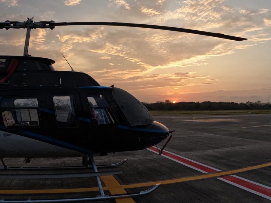 Helicóptero de Custom Aviation en plataforma controlada al atardecer